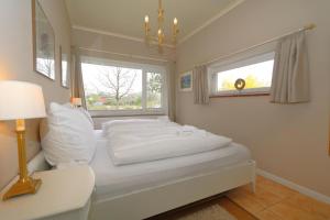 Un dormitorio blanco con una cama y una ventana. en Teewelkenhüs Wiesenappartement, en Archsum