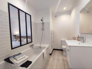 a white bathroom with a tub and a sink at La Chambre Jaune - Chambre avec salle de bain in Argenton-sur-Creuse