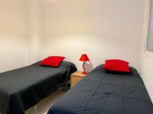 two beds in a room with red pillows and a lamp at Townhouse med takterrass i Costa Hispania in Gran Alacant