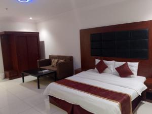 Una habitación de hotel con una cama grande y una silla. en أثير-النزهة, en Yeda