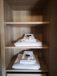 a closet with three towels and two pairs of shoes at Il piazzolo, un angolo di storia in Carobbio degli Angeli