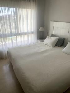 a bedroom with a large white bed with a window at Las Colinas Golf Club Residences Casa Encina 1 in Orihuela Costa +8 photos