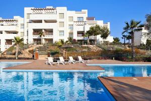 a swimming pool with lounge chairs and a building at Las Colinas Golf Club Residences Casa Encina 1 in Orihuela Costa