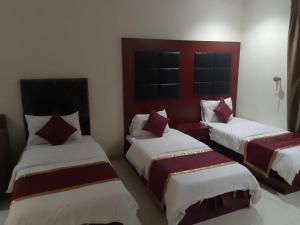 two beds in a room with red and white at أثير-النزهة in Jeddah +10 photos
