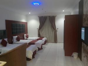 a hotel room with four beds and a blue light at أثير-النزهة in Jeddah