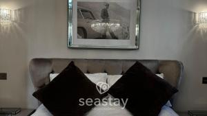 a picture on the wall above a bed with black pillows at Aurora Spa Seaview Penthouse Ramsgate in Kent