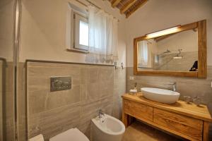 un bagno con lavandino, WC e specchio di Casa Andrea by PosarelliVillas a Siena Altre 18 foto