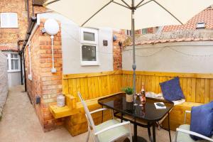 a patio with a table and an umbrella at Sandholme Cottage - Central location great for families in Filey +8 photos
