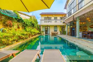 Una piscina con una sombrilla al lado de un edificio. en May Hoian Pool Villa, en Tân Thành (1)