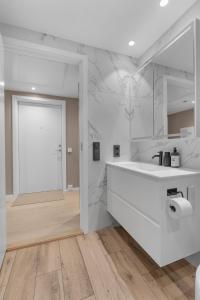 een witte badkamer met een witte wastafel en een deur bij Northstay - The Northview Retreat, Free Parking, Amazing Ocean Views in Tromsø