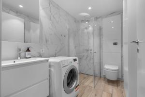 een witte badkamer met een wasmachine en een toilet bij Northstay - The Northview Retreat, Free Parking, Amazing Ocean Views in Tromsø +29 foto's