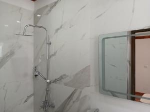 La salle de bains est pourvue d'une douche et d'un grand miroir. dans l'établissement Amaris Hotel, à Gjirokastër