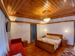 - une chambre avec un lit, un canapé et un plafond en bois dans l'établissement Amaris Hotel, à Gjirokastër