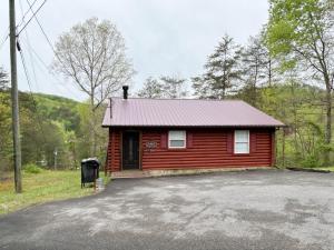 eine rote Hütte mit einem Parkplatz davor in der Unterkunft A Magical Experience in Pigeon Forge