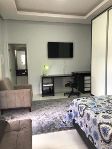 ein Schlafzimmer mit einem Bett und einem Schreibtisch mit einem Fernseher in der Unterkunft Sua casa fora de casa, ao lado do shopping in Jacuda