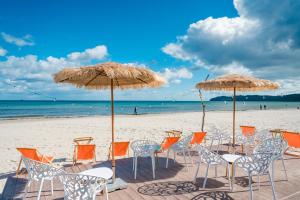 eine Gruppe von Stühlen und Sonnenschirmen an einem Strand in der Unterkunft Arkona Strandhotel in Binz