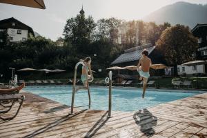 a man and woman jumping into a swimming pool at Resl Resort in Flachau