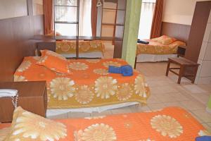 um quarto com três camas com lençóis laranja em Hotel Mitru em Tupiza