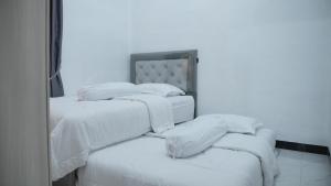 a group of three beds with white sheets and pillows at Aljazeera Residence in Lamnyong
