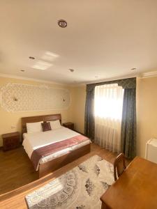 a bedroom with a bed and a table and a window at Sky Luxe Hotel in Astana