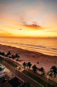 Apartamento Sol Nascente في برايا جراندي: غروب الشمس على الشاطئ مع أشجار النخيل والمحيط