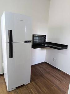 a white refrigerator with a microwave on top of it at Residencial Luce Del Sole - Apto N º 1 in Joinville