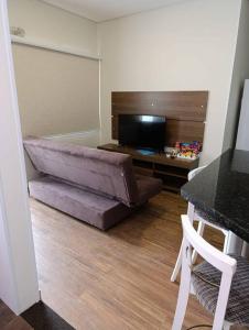 a living room with a bed and a desk at Residencial Luce Del Sole - Apto N º 1 in Joinville