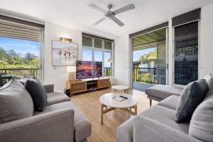a living room with two couches and a flat screen tv at Panoramic Ocean Penthouse in Noosa Heads