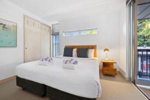 a bedroom with a large white bed and a window at Panoramic Ocean Penthouse in Noosa Heads