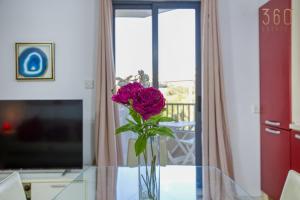 eine Vase mit einer rosa Blume auf einem Glastisch in der Unterkunft Lovely 1BR Apt with private balcony in Gzira by 360 Estates in Gżira
