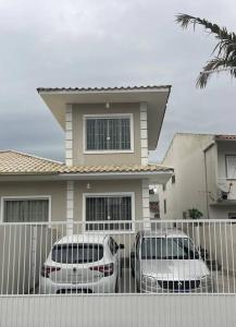 two cars parked in front of a house at Loft Studio 101 em São José à 7km de Floripa in São José