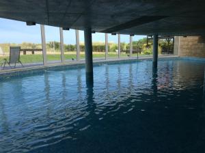 una piscina de agua con columnas en un edificio en Linda Bay spa playa Unidad 603 Mar de Las Pampas, en Mar de las Pampas
