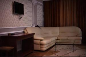 a living room with a white couch and a tv at Sky Luxe Hotel in Astana