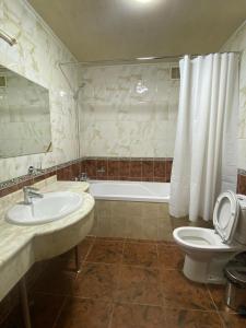 a bathroom with a sink and a toilet and a tub at Sky Luxe Hotel in Astana