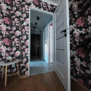 a hallway with pink flowers on the wall at Apartament Okrzei in Włocławek
