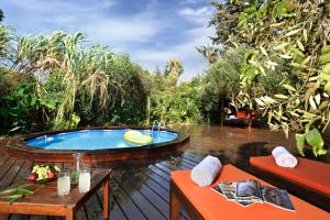a patio with a jacuzzi tub in a garden at Spa Chalets In Olive Grove in Eli Ad