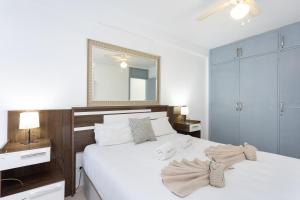 Un dormitorio con una cama con sábanas blancas y un espejo. en Urbanización Viña del Mar VIV, en Playa Fañabe 17 fotos más