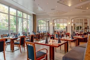 ein Restaurant mit Tischen und Stühlen und Fenstern in der Unterkunft Arkona Strandhotel in Binz
