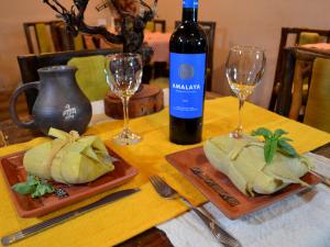 - une table avec deux assiettes de nourriture et une bouteille de vin dans l'établissement La Casa del Tata, à Maimará
