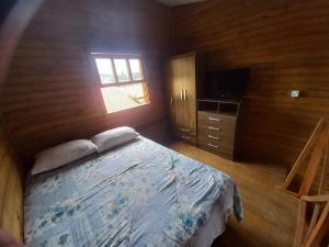 a bedroom with a bed and a window and a television at Pousada Belas Praias Lofts da Riba in Imbituba