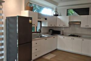a kitchen with white cabinets and a stainless steel refrigerator at The Loft House Elyu in San Fernando