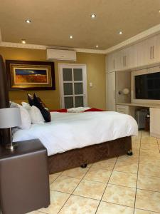 a large bedroom with a large bed with white sheets at Romans Rest Guest House in Carletonville