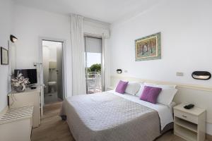 biała sypialnia z łóżkiem z fioletowymi poduszkami w obiekcie Hotel Gioiello w Cesenatico +29 zdjęć