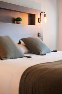 a close up of a bed with two pillows on it at Appart'hôtel Le Corot - Accès Autonome - Saint-Junien Centre in Saint-Junien