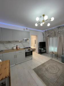 een keuken met witte kasten en een woonkamer bij Victoriei Light&Comfort in Boekarest