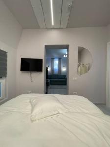 een slaapkamer met een wit bed en een televisie bij Victoriei Light&Comfort in Boekarest