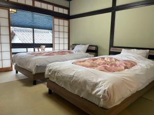 two beds in a room with two windows at 湯宿ささくら in Kinosaki