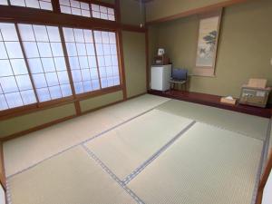an empty room with a refrigerator and windows at 湯宿ささくら in Kinosaki