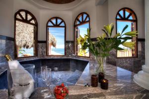 a kitchen with a table with a vase of flowers and windows at Villa Celeste in Puerto Vallarta
