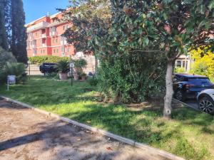 ein neben einem Baum und einem Gebäude geparktes Auto in der Unterkunft Hotel Delta Florence in Calenzano
